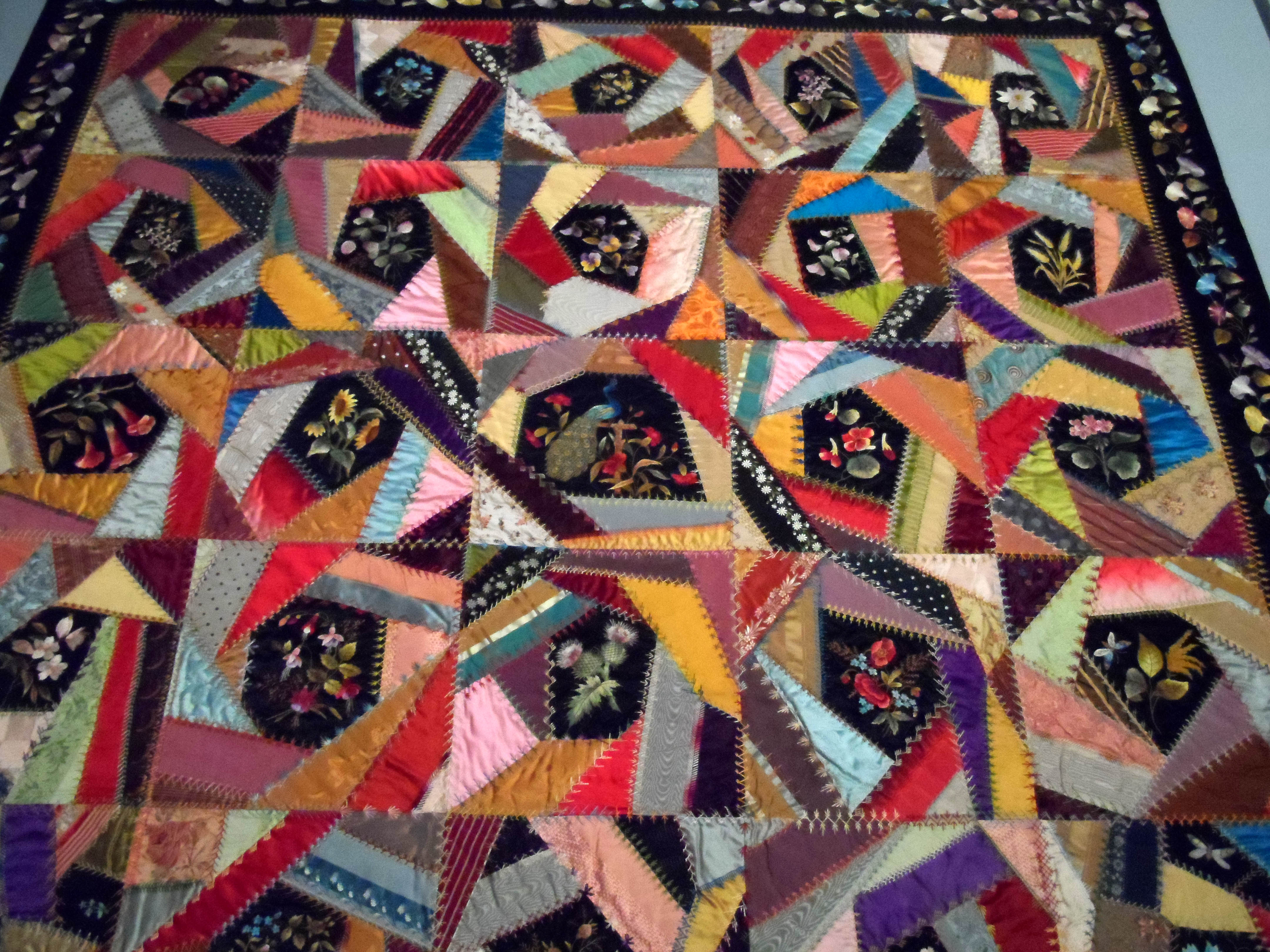 detail of CRAZY QUILT, circa 1880, silk. There is an embroidered flower in the centre of each block. It was made by Mary Stinson, who was a professional dressmaker