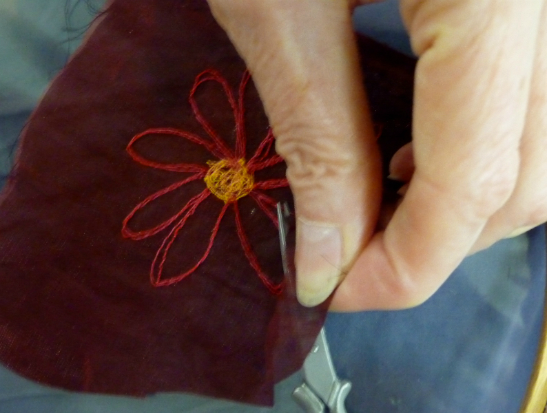 cutting the fabric away from a machine embroidered flower