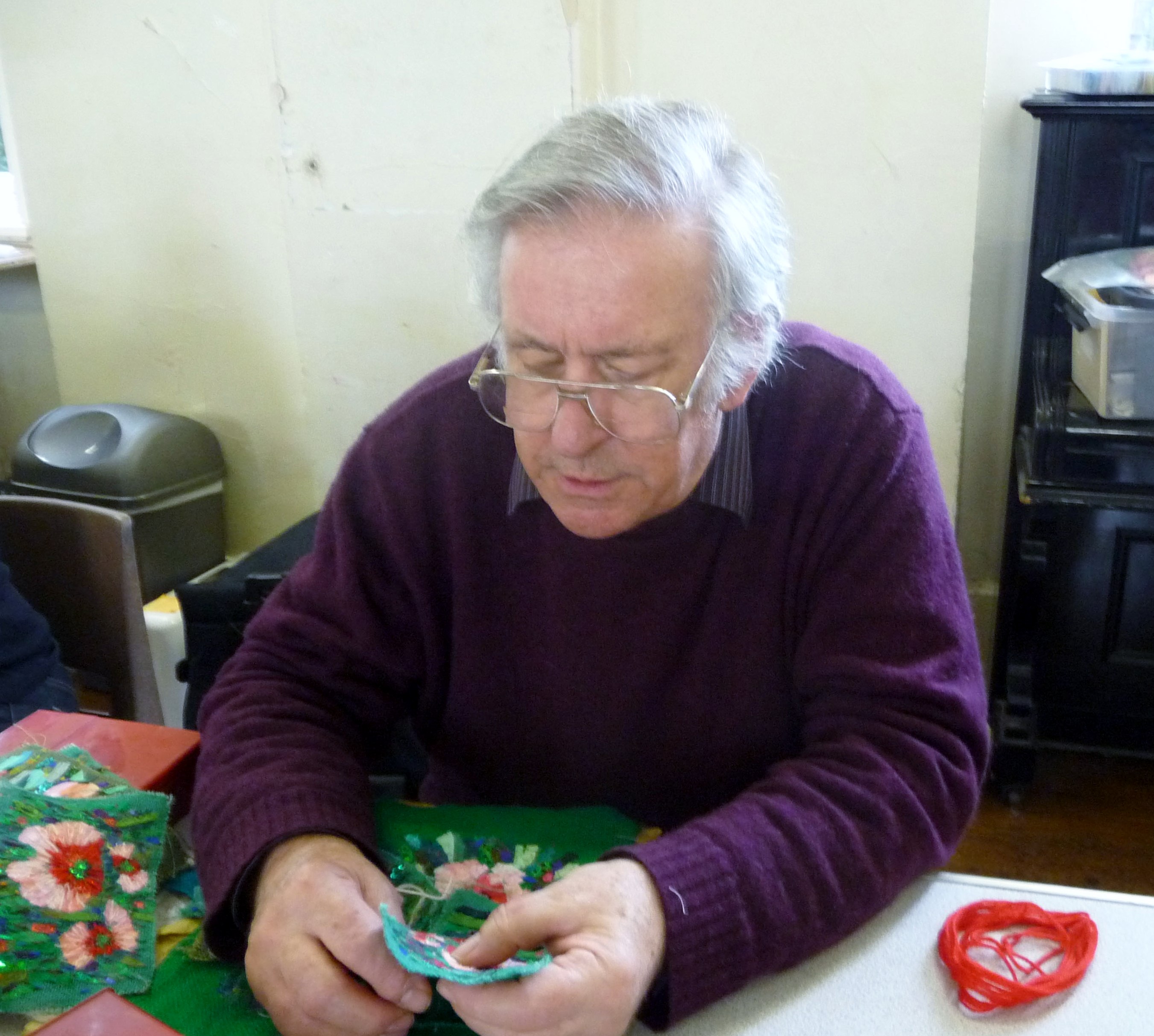 Richard Box is demonstrating how to hand stitch the flowers at "Poppies" workshop at MEG