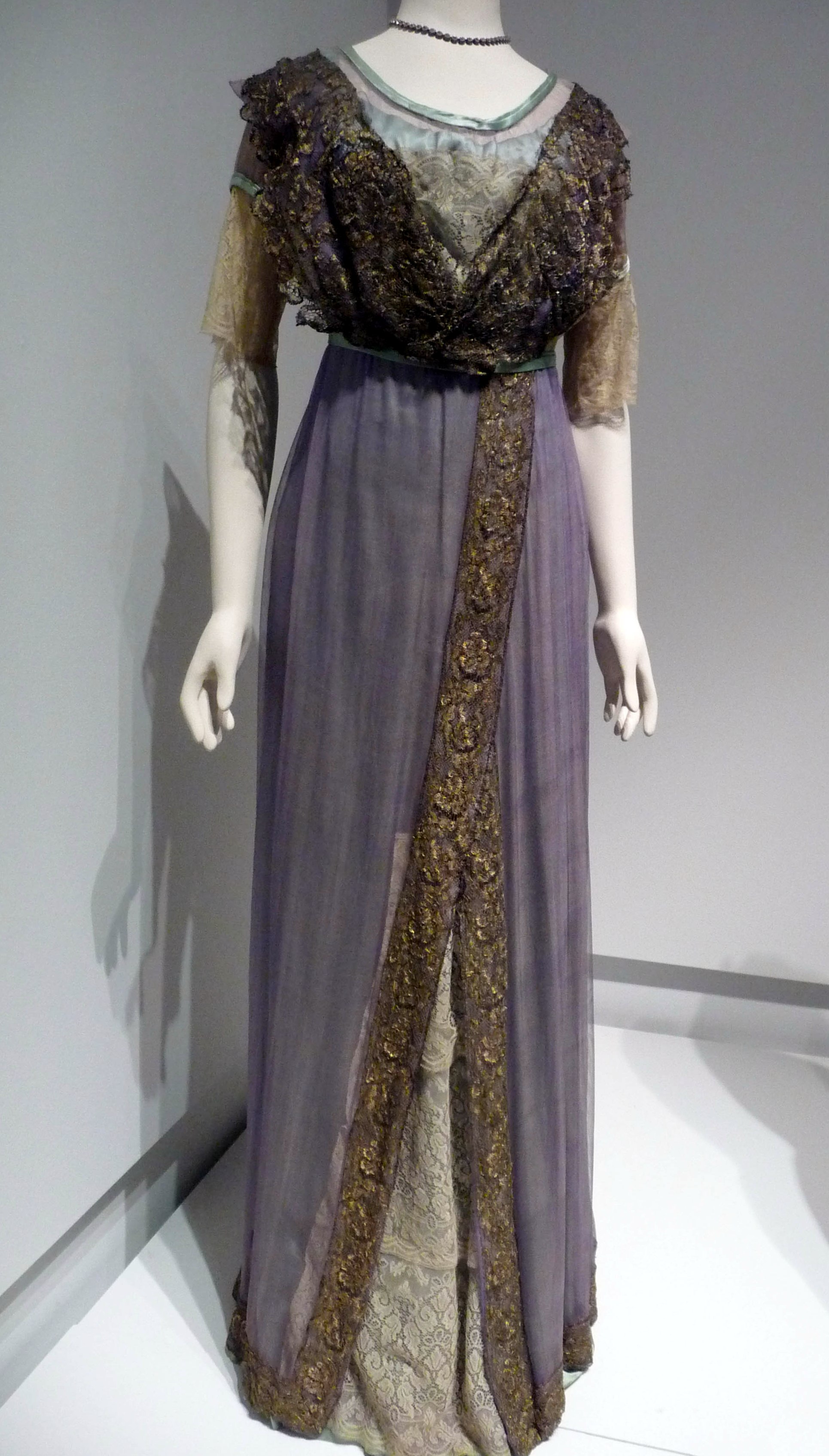 EVENING DRESS WITH TRAIN, silk satin, marquisette net and machine-made lace, trimmed with gold metallic lace, made by T&S Bacon, Liverpool, 1911-13.