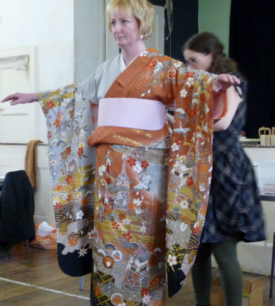 the kimono is draped over a belt to adjust the length and a stiff belt is put on to prevent the Obi creasing