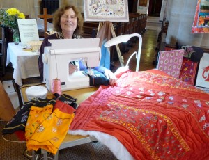 Norma is quilting some strips of fabric, hand embroidered in Sreepur, to make a quilt