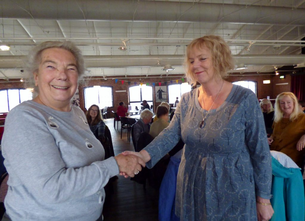 Mal Ralston won Visitor's Vote at Endeavour exhibition 2018 for her embroidery MAORI MAN. She is being congratulated by MEG Chair Vicky Williams.